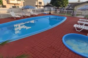 una gran piscina con sillas y sombrillas en un patio en Kit 6 Residencial Diego Marcelo, en Itapema