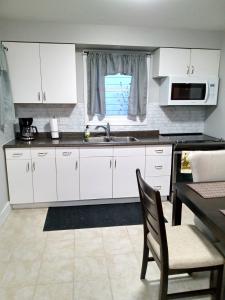a kitchen with white cabinets and a sink and a table at Toronto Furnished Living- Niagara Falls in Niagara Falls