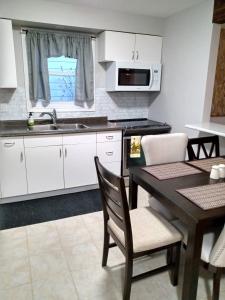 a kitchen with white cabinets and a table and a sink at Toronto Furnished Living- Niagara Falls in Niagara Falls