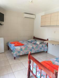 1 dormitorio con 2 camas, mesa y nevera en Pousada Caminhos da Praia, en Penha