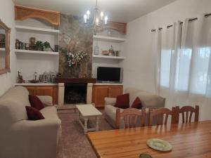 sala de estar con sofá, mesa y TV en Encantadora casa rural con gran porche en San Roque