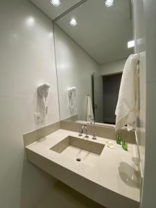 a bathroom with a sink and a large mirror at KEEP SUÍTES HOTEL in Taubaté