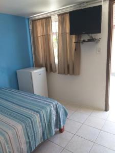 1 dormitorio con 1 cama y TV de pantalla plana en Pousada Caminhos da Praia, en Penha