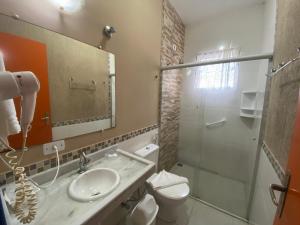 a bathroom with a toilet a sink and a mirror at Kaliman Pousada in Ubatuba