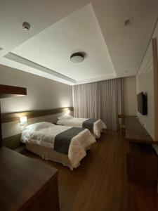 een hotelkamer met twee bedden en een televisie bij KEEP SUÍTES HOTEL in Taubaté