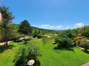 a view of a green field with trees and bushes at L'Oustaou du Luberon et SPA in Villelaure