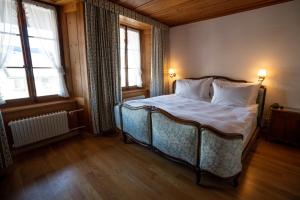 a bedroom with a bed with white sheets and two windows at La Fleur de Lys in Gruyères