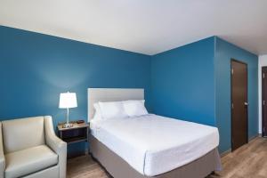 a blue bedroom with a bed and a chair at WoodSpring Suites Chicago Addison in Addison