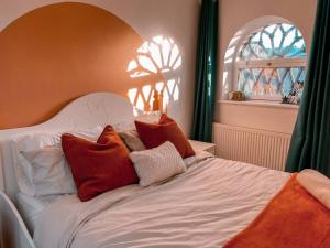 Una cama blanca con almohadas rojas y blancas. en Riverside loft apartment, en Newport
