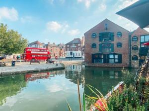 un bus rouge à deux étages est garé à côté d'une rivière. dans l'établissement Riverside loft apartment, à Newport