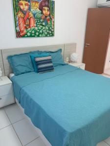 a bedroom with a blue bed with a painting on the wall at Condomínio Lírios Paraíso de Paz e Beleza in Mata de Sao Joao