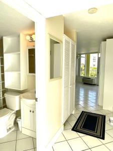a white bathroom with a toilet and a sink at Ocean Overlook - Sea View at Symphony Beach Club! in Ormond Beach