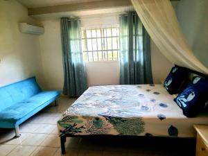 a bedroom with a bed and a couch and a window at Seru Coral Apartment in Willemstad