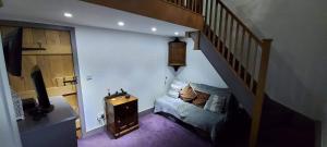 a bedroom with a staircase with a bed and a television at Colts Neck Cottage Upper Hopton, Mirfield, West Yorkshire in Mirfield