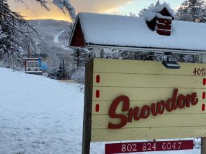 a snow covered sign next to a snow covered mountain at Snowdon Chalet Motel in Londonderry