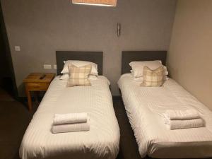 two beds in a room with towels on them at Duke Of York in Hazel Grove