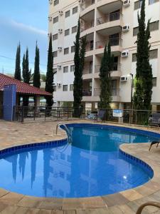 a large swimming pool in front of a building at Apartamento Villagio in Olímpia