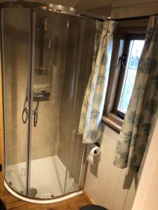 a shower with a glass door in a bathroom at Woody's Retreat in Bolton by Bowland
