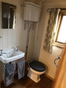 a bathroom with a black toilet and a sink at Woody's Retreat in Bolton by Bowland