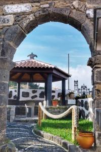 um arco numa parede de pedra com um gazebo em Ribeirinha House em Porto Formoso