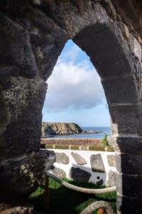 a view of the ocean through a stone window at Ribeirinha House in Porto Formoso