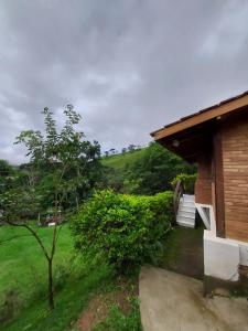 a house with a green hill in the background at Chales Edelweiss in Visconde De Maua