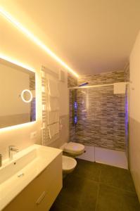 een badkamer met een toilet, een wastafel en een spiegel bij Residence Albierch in Ortisei