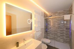 uma casa de banho com um lavatório, um WC e um espelho. em Residence Albierch em Ortisei