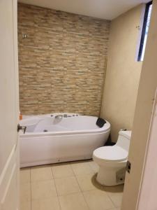 a bathroom with a white tub and a toilet at Departamentos La Estación del tren in Riobamba