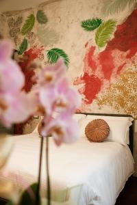 a bed with pink flowers in front of a wall at BED and BREAKFAST il Duomo in Ascoli Piceno