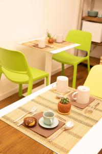 une table avec des chaises vertes et une table avec des tasses à café dans l'établissement BED and BREAKFAST il Duomo, à Ascoli Piceno