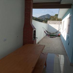een kamer met een tafel en een hangmat aan een muur bij Casa em Caraguatatuba Praia Massaguaçu/Cocanha in Caraguatatuba