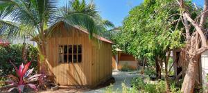 Bugambilias Alojamiento في Brisas de Zicatela: منزل خشبي صغير في حديقة بها أشجار نخيل