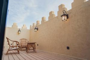 een patio met een tafel en stoelen aan een muur bij Malfakum Al Diriyah in Riyad