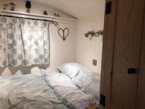 an unmade bed in a bedroom with a window at Woody's Retreat in Bolton by Bowland