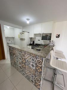 a kitchen with a marble counter top and white cabinets at Paraíso das Águas in Camaçari