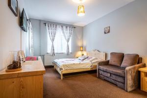 a bedroom with a bed and a couch and a chair at Willa Cicha Woda Centrum in Zakopane