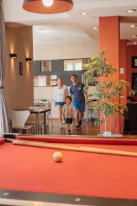 a family walking through a room with a pool table at Tangoinn Club Hotel in San Carlos de Bariloche