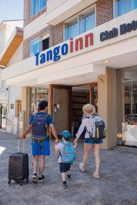 two adults and a child walking out of a hotel at Tangoinn Club Hotel in San Carlos de Bariloche