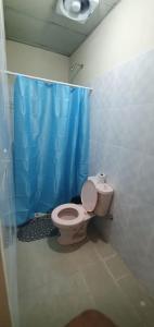 a bathroom with a toilet and a blue shower curtain at Hostal Brisas Calobrenas in Calobre
