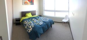 a bedroom with a bed with a blue comforter and a window at Departamento Familiar con vista al Mar in Coquimbo