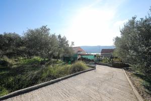 una passerella con alberi e una casa sullo sfondo di Apartments Tara - 70 m from beach a Brbinj