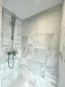 La salle de bains est pourvue d'une douche et de murs en marbre blanc. dans l'établissement BNBHolder PALACIO DE CRISTAL es MIA, à Madrid