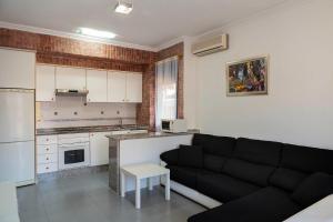 a living room with a black couch and a kitchen at Apartamento planta baja en playa Canet de Berenguer in Canet de Berenguer