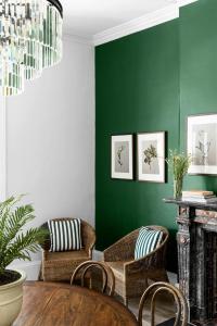 a living room with green walls and wicker chairs at Hotel Challis Potts Point in Sydney