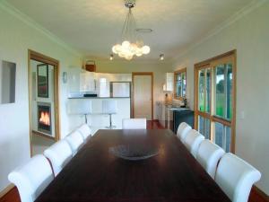 a dining room with a table and white chairs at Kinsale Cottage in Pokolbin