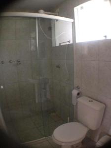 a bathroom with a shower with a toilet and a glass door at Pousada Dunas Da Joaquina in Florianópolis