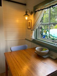 a dining room with a wooden table and a window at Shepherd's Cottage in Evandale