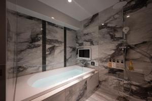 a bathroom with a tub and a tv on the wall at HOTEL VARKIN Ikebukuro Nishiguchi in Tokyo