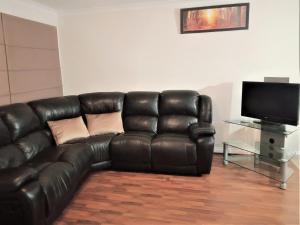 een zwarte leren bank in een woonkamer met een televisie bij 2BR luxury house in Piccadilly in Kalgoorlie